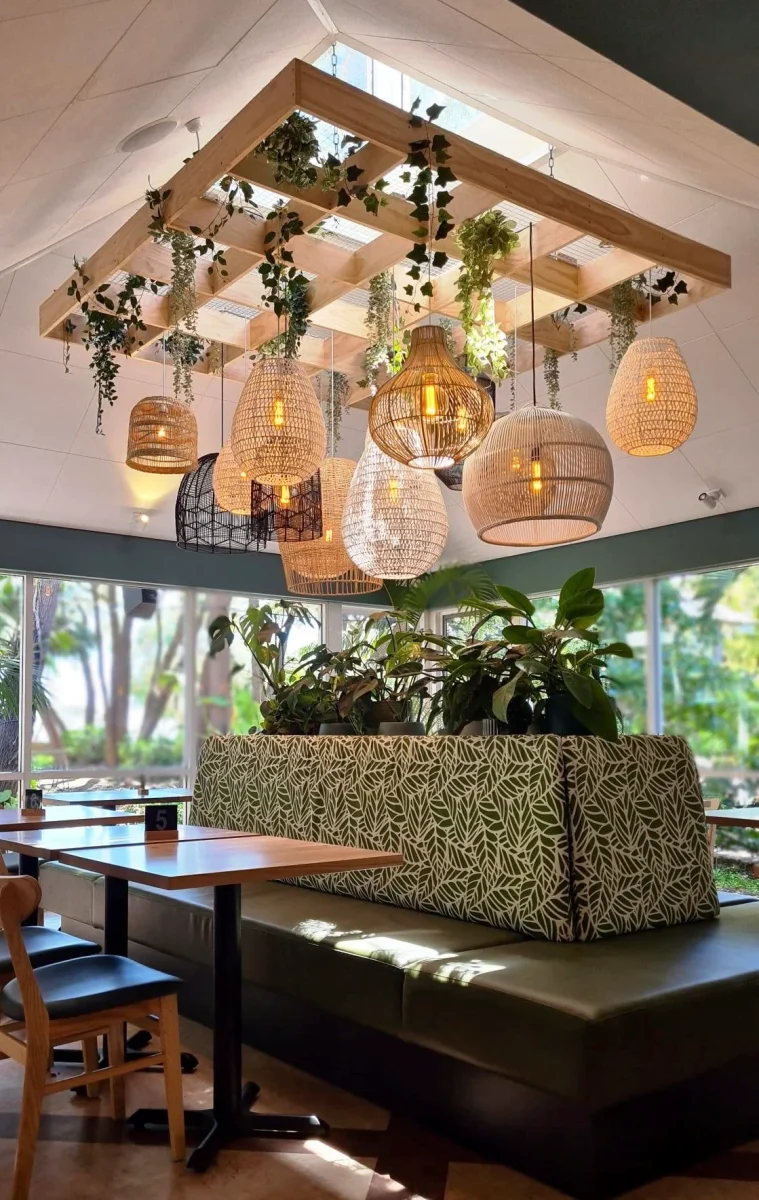 Custom upholstered booth seating at Tonic by the Bay, featuring leafy green fabric, pendant rattan lighting, and solid timber tables crafted by Robinson Group in Busselton, Western Australia.