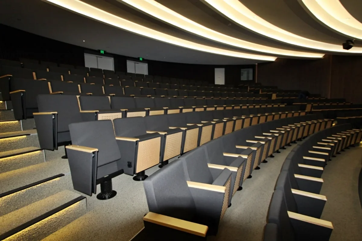 Custom commercial auditorium seating with upholstered chairs and timber armrests installed for Woodside Energy corporate facility in Western Australia
