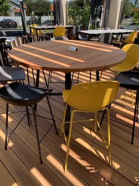 Round Lady table with solid timber top surrounded by yellow and black outdoor barstools at the Inglewood Hotel alfresco area.