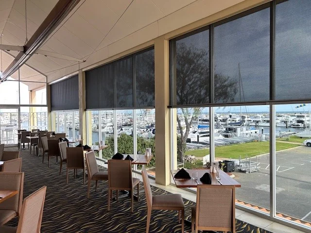 Marina-view dining space at Hillarys Yacht Club featuring Juniper dining chairs and bespoke solid Marri dining tables.
